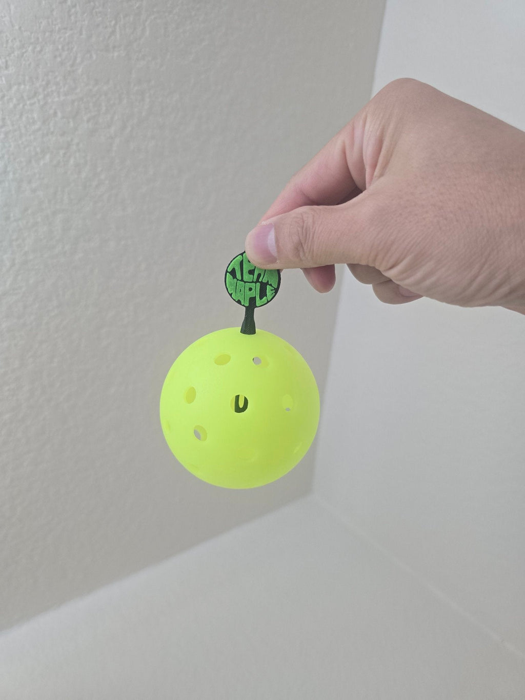 Ball picker inserted in a pickleball, lifting it